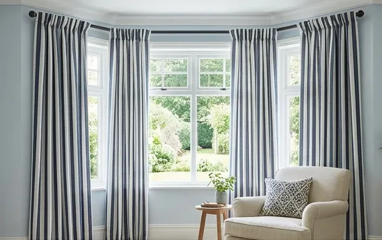 Blue and white vertical-stripe pinch-pleat curtains across a bay window