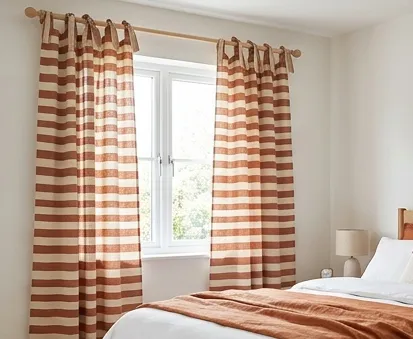 Full-length rust and cream horizontal-stripe tab-top curtains in a bedroom
